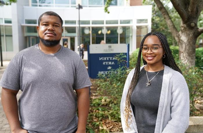 Two people stand in front of a building on ODU's campus.